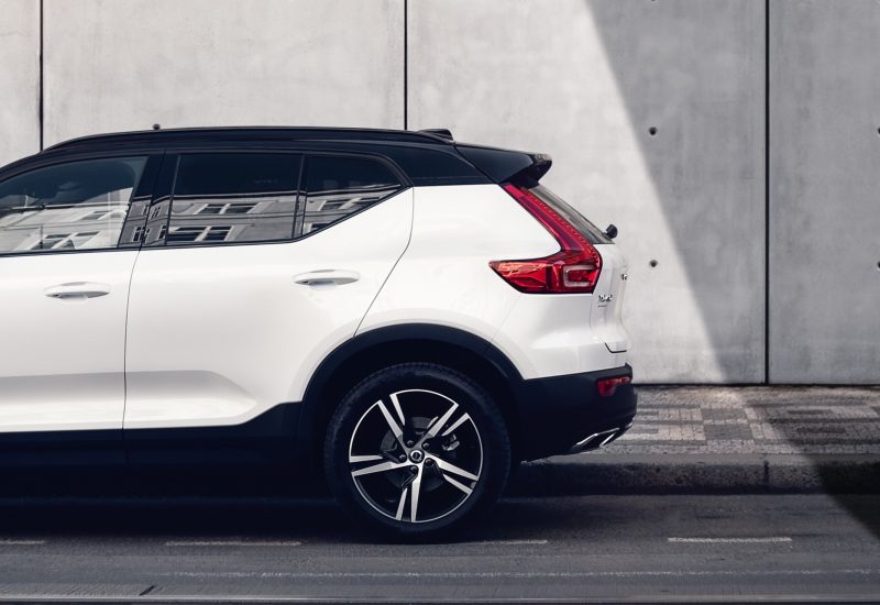 Side view of a white Volvo SUV parked by a concrete wall. Binar Solutions has been supporting Volvo with various solutions for over two decades.