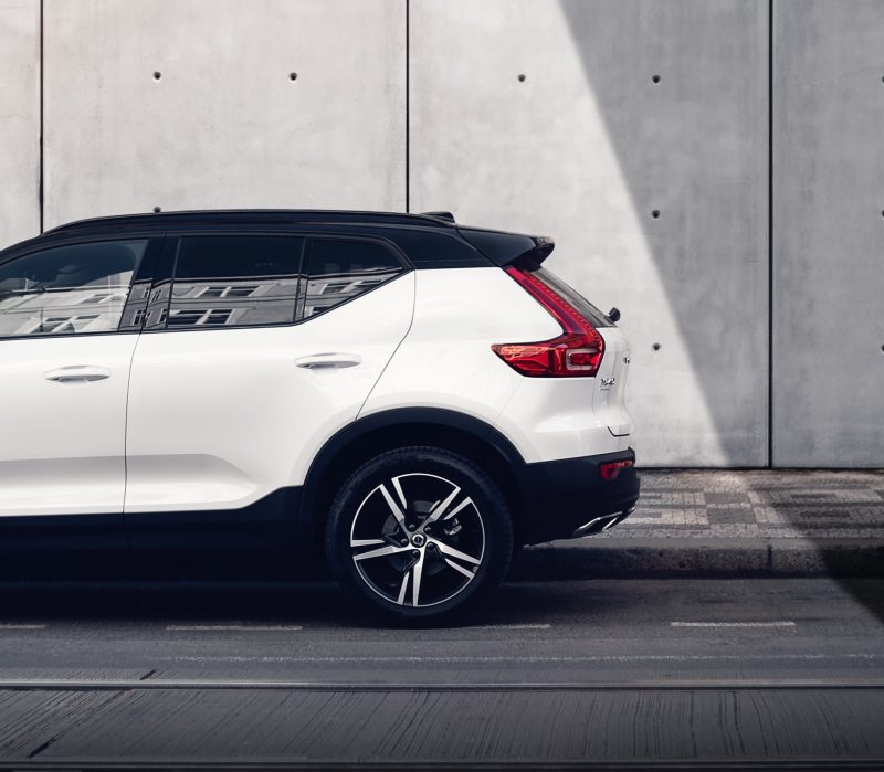 Side view of a white Volvo SUV parked by a concrete wall. Binar Solutions has been supporting Volvo with various solutions for over two decades.